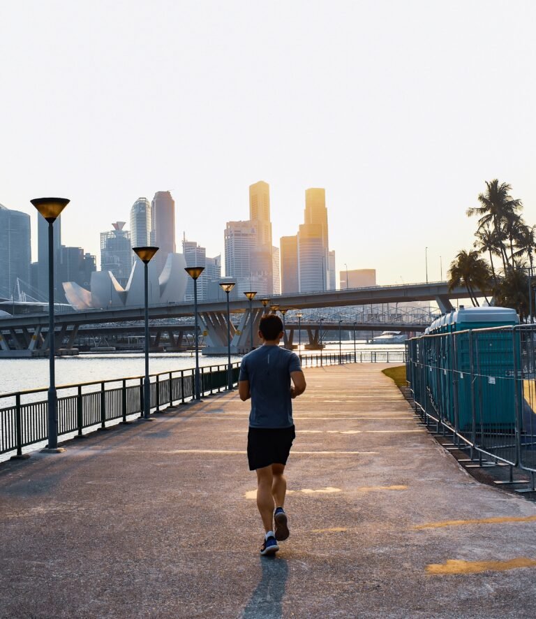 man jogging next to river in a large city